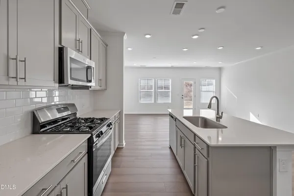 a kitchen with stainless steel appliances granite countertop white cabinets and a stove top oven