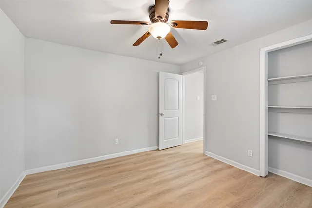 a view of an empty room with window and a ceiling fan