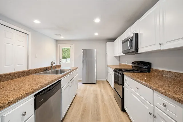 a large kitchen with stainless steel appliances granite countertop a lot of counter space and wooden floors