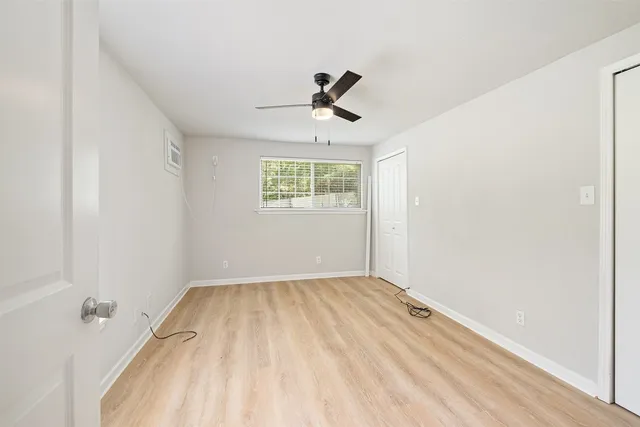 an empty room with a window and a ceiling fan