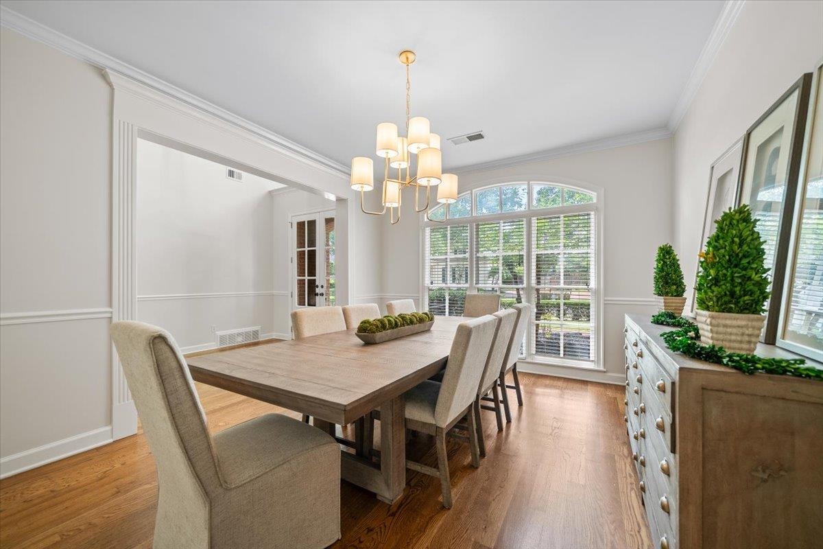 1876 Liles Lane Collierville, TN 38017 - Photo 16 of 36 Dining area featuring hardwood flooring, an arched window with blinds, a multi-arm chandelier, and decorative wainscoting