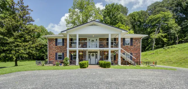 a view of a brick house next to a yard with big trees