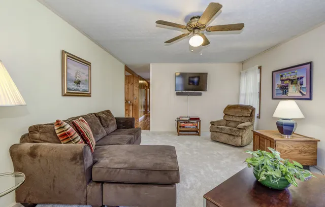 a living room with stainless steel appliances furniture a rug kitchen view and a large window