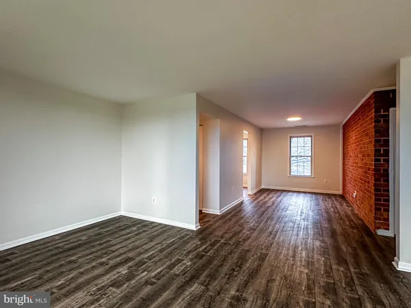 an empty room with wooden floor cabinet and windows