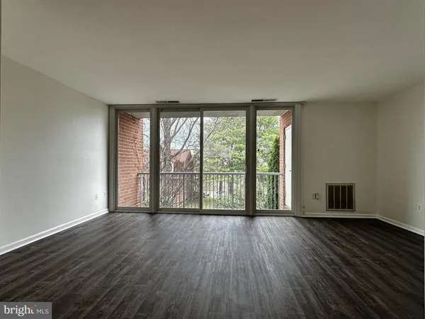 a view of an empty room with wooden floor and doors