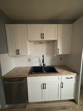 a kitchen with granite countertop white cabinets and black appliances