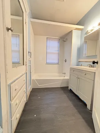 a bathroom with a bathtub sink mirror vanity and a toilet
