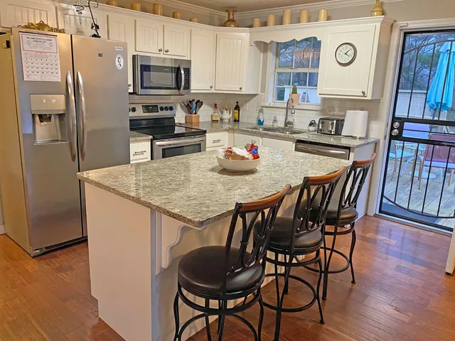 a kitchen with stainless steel appliances kitchen island granite countertop a sink refrigerator and microwave