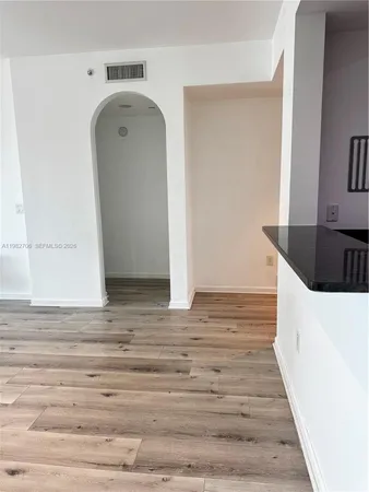 a kitchen with stainless steel appliances granite countertop a refrigerator a stove a microwave oven and a sink with wooden floor