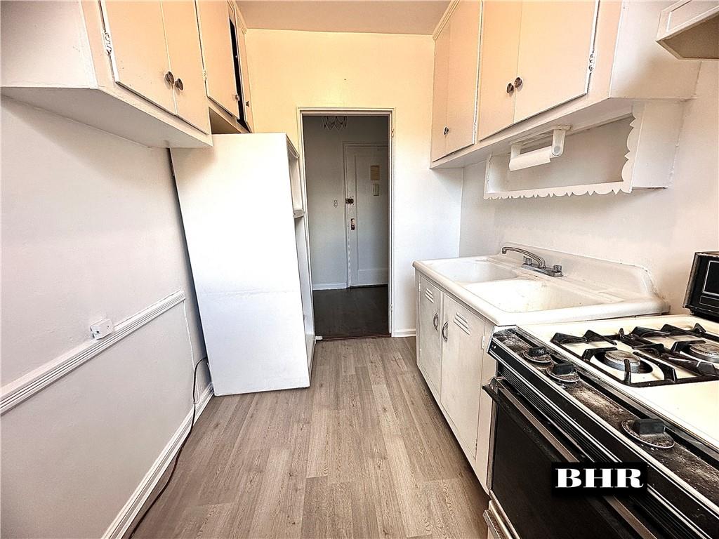 2615 Homecrest Avenue, Unit 6B Brooklyn, NY 11235 - Photo 6 of 17 a kitchen with stainless steel appliances a refrigerator a sink and wooden floors