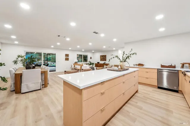 a kitchen with stainless steel appliances kitchen island sink stove and white cabinets with wooden floor