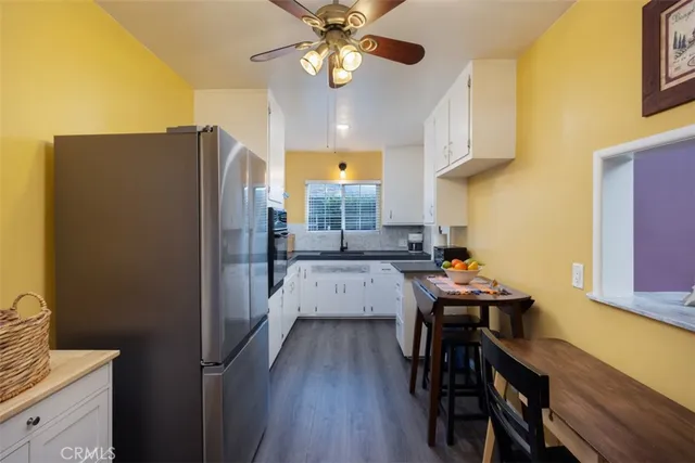 a kitchen with stainless steel appliances granite countertop a refrigerator a sink dishwasher a stove and a dining table with wooden floor