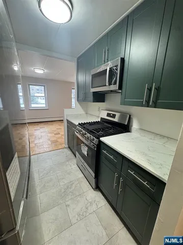 a kitchen with stainless steel appliances granite countertop a stove a sink and a microwave