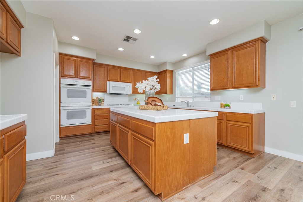 14236 Pointer Loop Eastvale, CA 92880 - Photo 13 of 38 a kitchen with stainless steel appliances granite countertop a sink stove cabinets and wooden floor