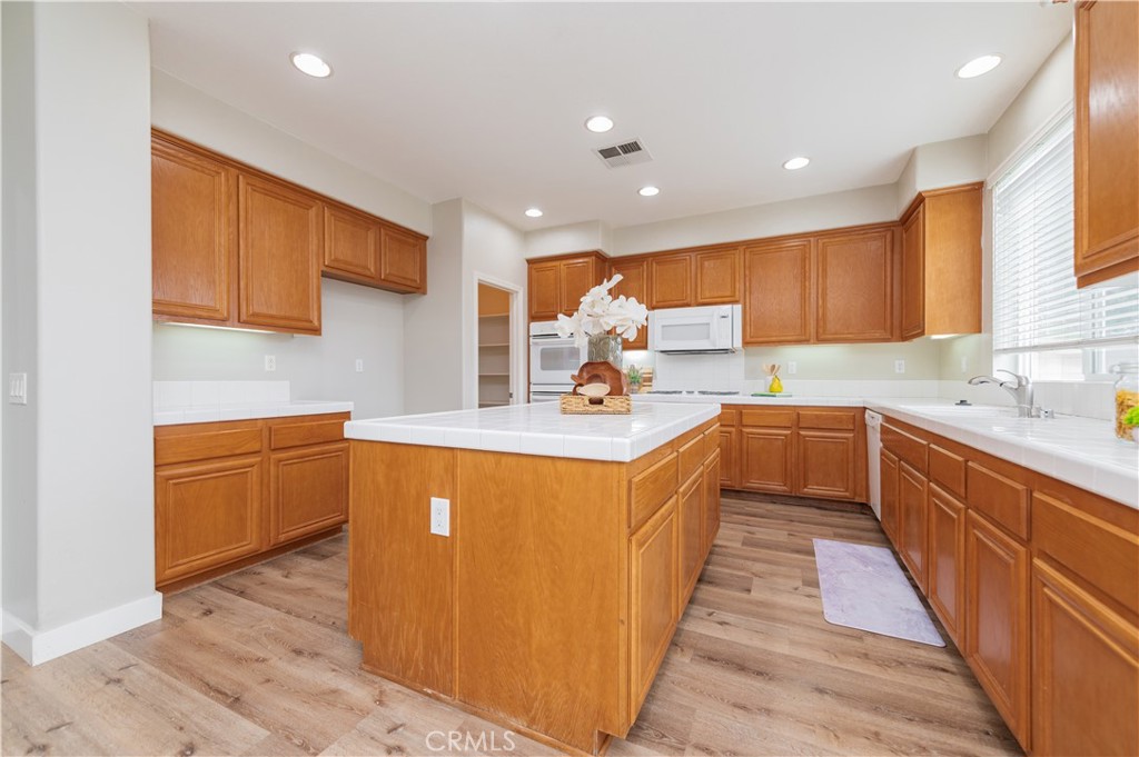 14236 Pointer Loop Eastvale, CA 92880 - Photo 14 of 38 a kitchen with stainless steel appliances granite countertop a sink a stove a refrigerator cabinets and wooden floor