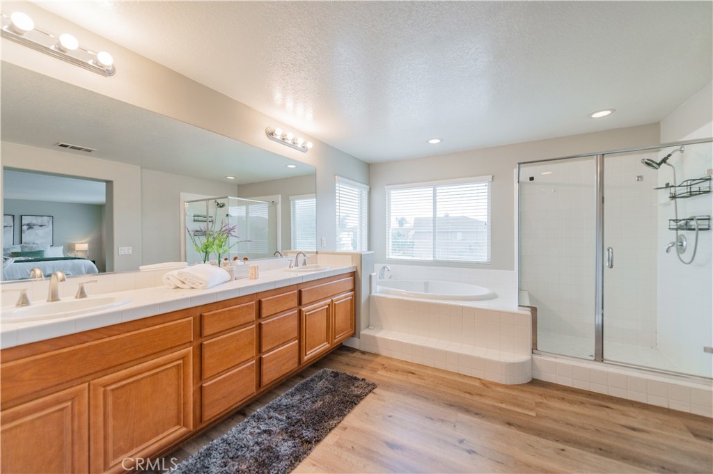 14236 Pointer Loop Eastvale, CA 92880 - Photo 28 of 38 a spacious bathroom with double vanity a large mirror and a bathtub