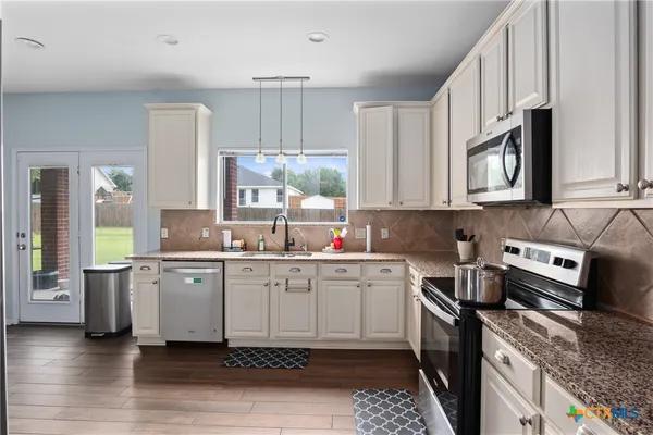 a kitchen with stainless steel appliances granite countertop a sink stove and cabinets