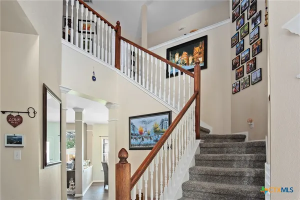 a view of staircase with lots of frames on wall and wooden floor