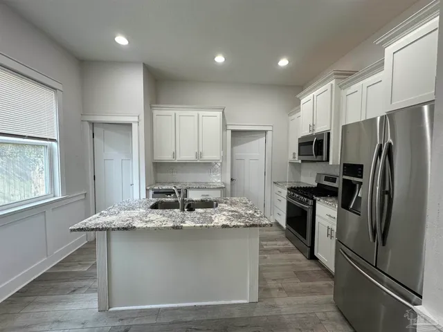 a kitchen with kitchen island stainless steel appliances a sink stove refrigerator and cabinets