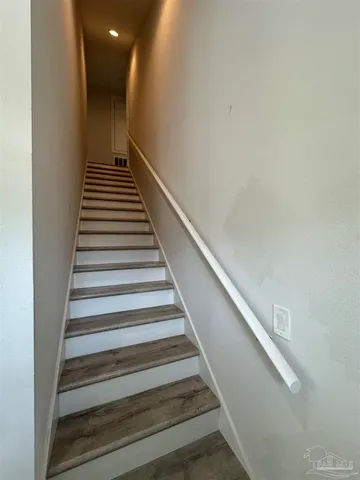 a view of an empty room with wooden floor and a ceiling fan
