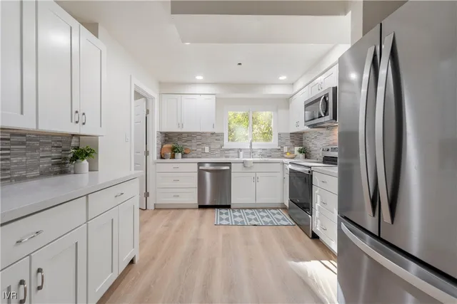 a kitchen with white cabinets stainless steel appliances and window