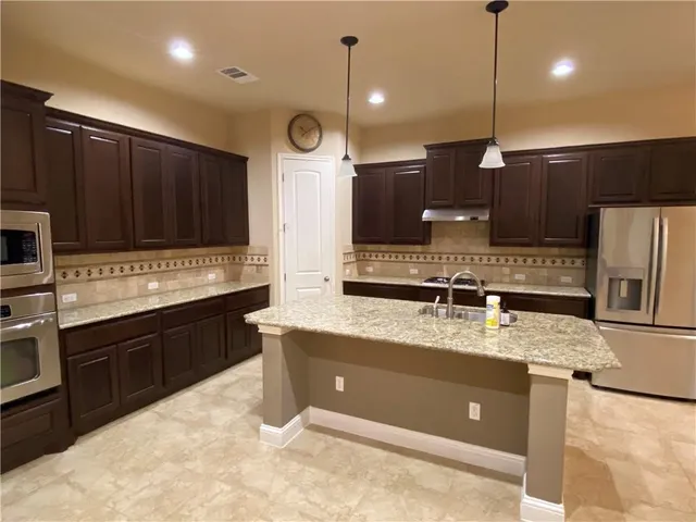 a kitchen with a sink a counter space appliances and cabinets