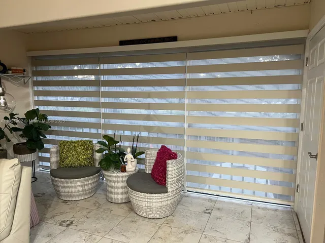 a living room with furniture a flat screen tv and a floor to ceiling window