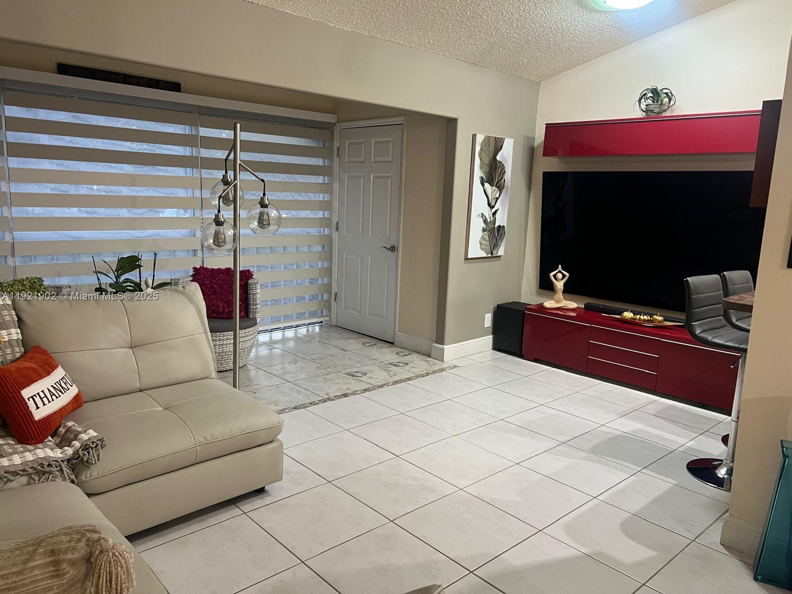 9446 Southwest 140th Court, Unit 9446 Miami, FL 33186 - Photo 9 of 48 a living room with furniture a flat screen tv and a floor to ceiling window