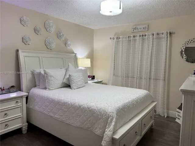 a bedroom with a bed and a flat tv screen on dresser