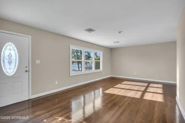 a view of an empty room with window and wooden floor