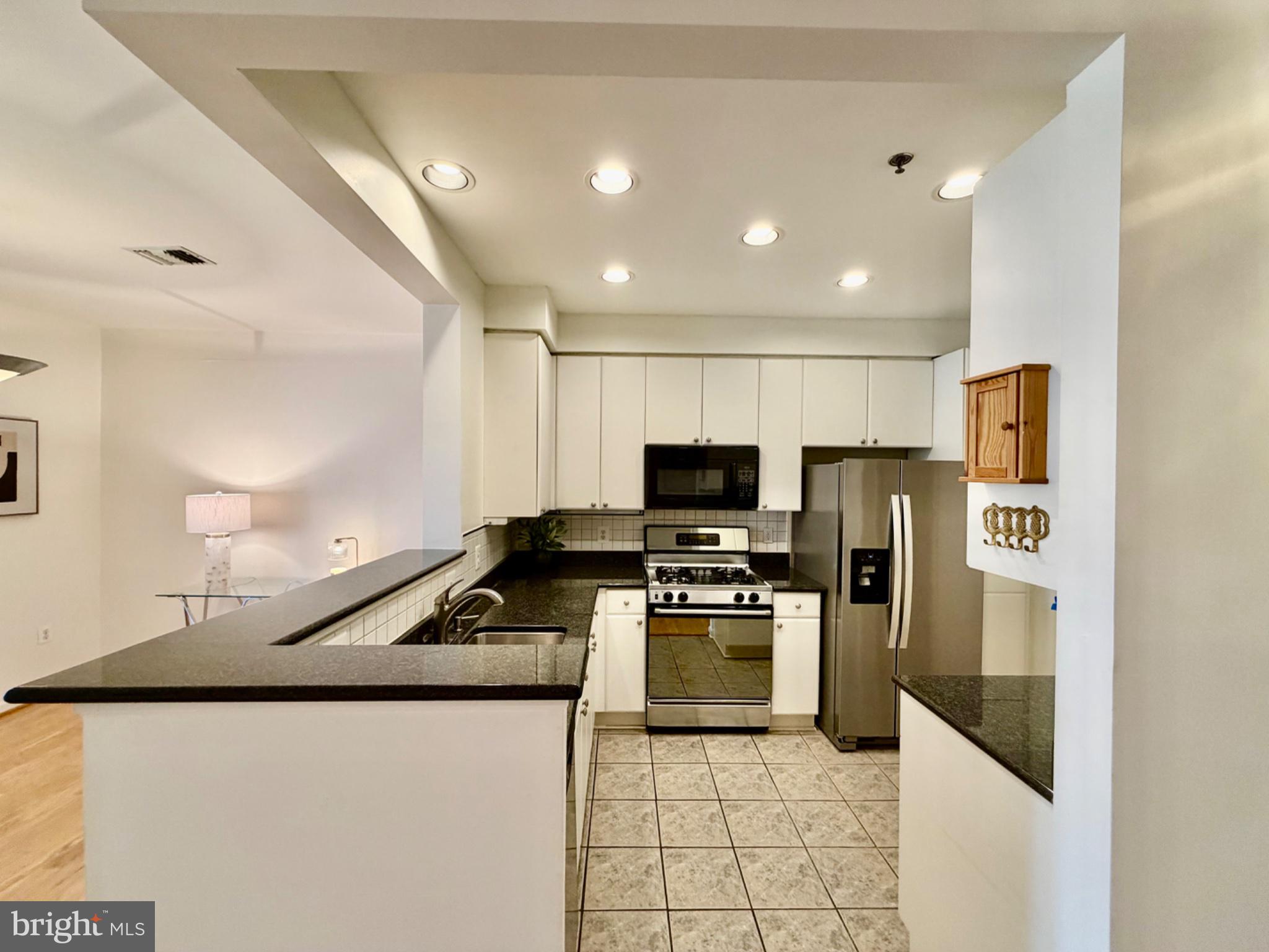1855 Stratford Park Place, Unit 214 Reston, VA 20190 - Photo 9 of 29 a kitchen with stainless steel appliances a refrigerator a stove a sink a stove a oven with white cabinets