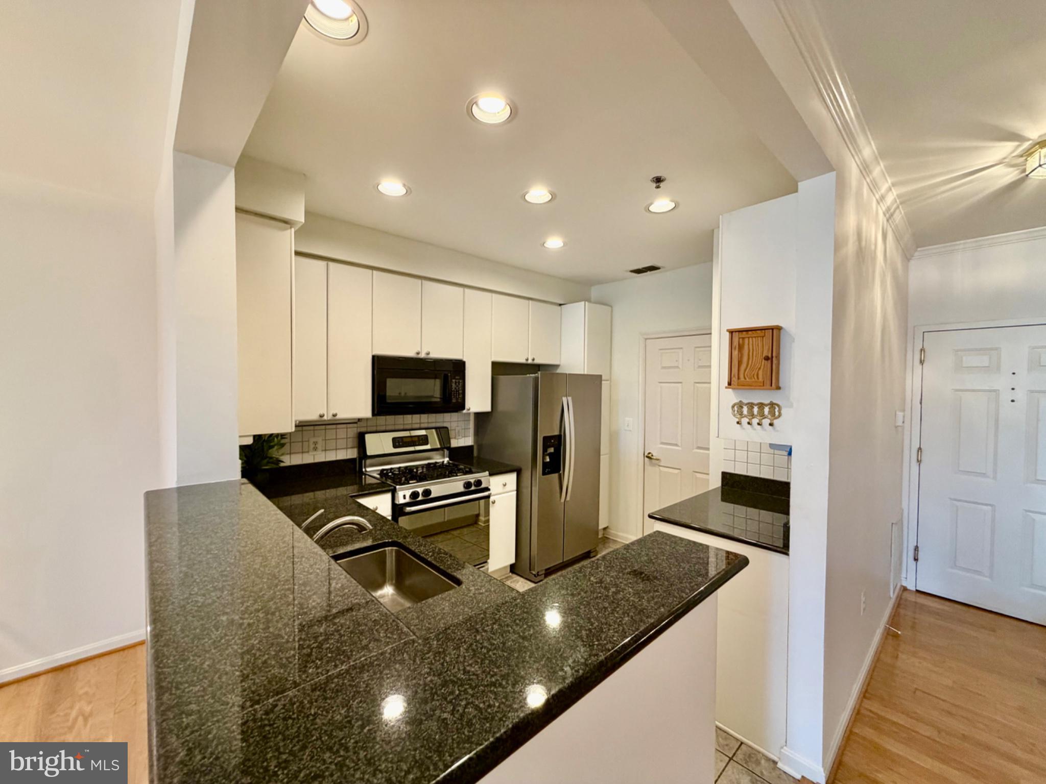 1855 Stratford Park Place, Unit 214 Reston, VA 20190 - Photo 10 of 29 a kitchen with stainless steel appliances granite countertop a sink refrigerator and microwave