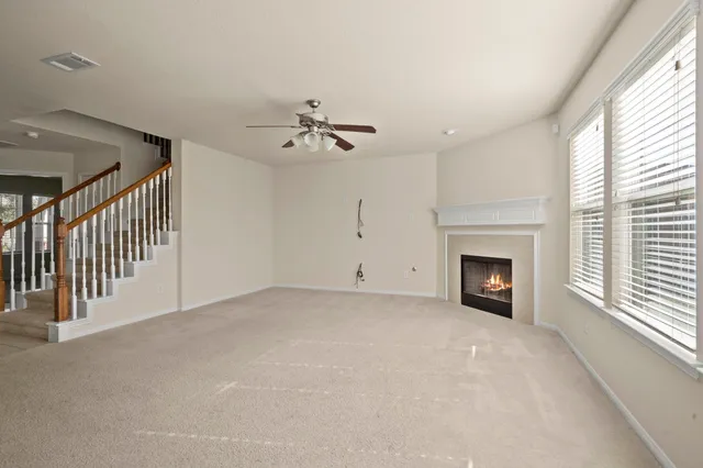 a view of an empty room with a fireplace and a ceiling fan