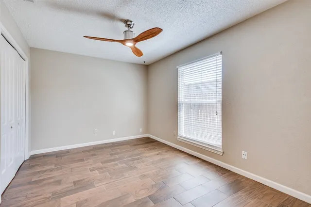 a view of empty room with wooden floor and fan