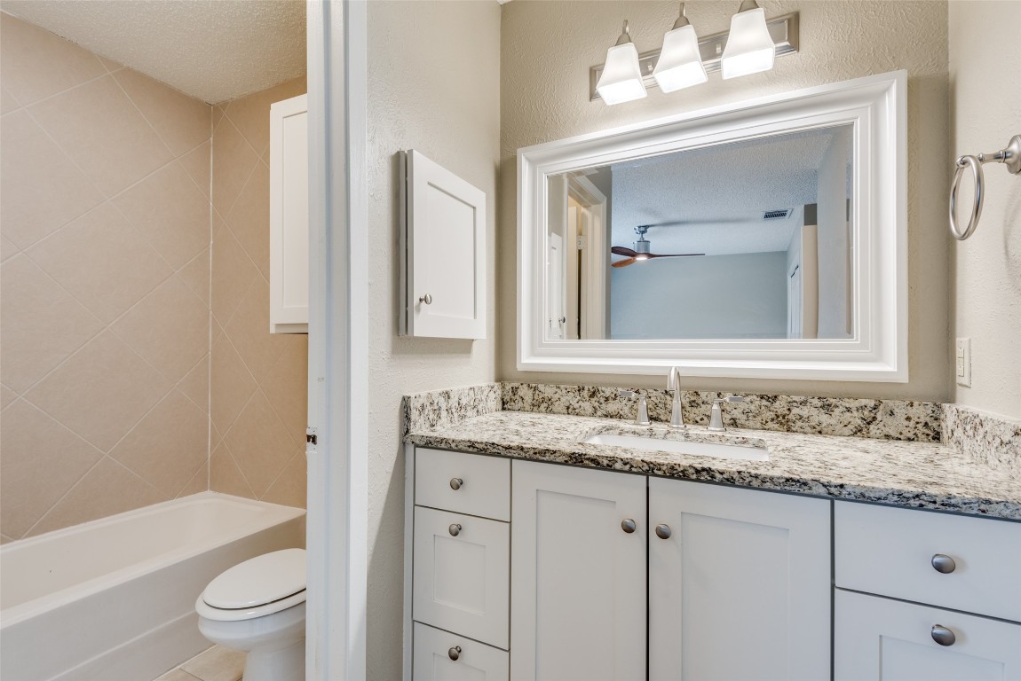3603 Leafield Drive, Unit A Austin, TX 78749 - Photo 8 of 12 a bathroom with a granite countertop sink vanity mirror bathtub shower and a toilet