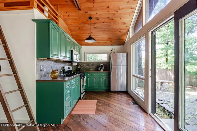 a kitchen with stainless steel appliances granite countertop a refrigerator a sink dishwasher a stove and a dining table with wooden floor