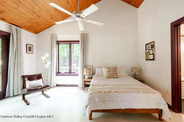 a bedroom with a bed a chair and a large window