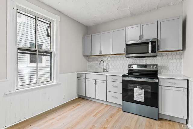 a kitchen with granite countertop cabinets stainless steel appliances and wooden floor