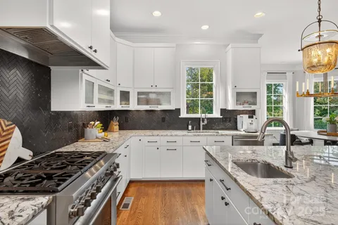 a large white kitchen with lots of wooden furniture and appliances
