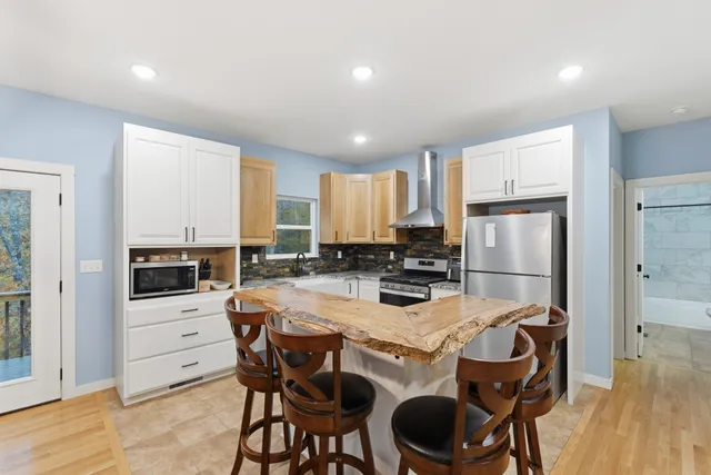 a kitchen with stainless steel appliances kitchen island granite countertop a dining table chairs stove refrigerator and cabinets