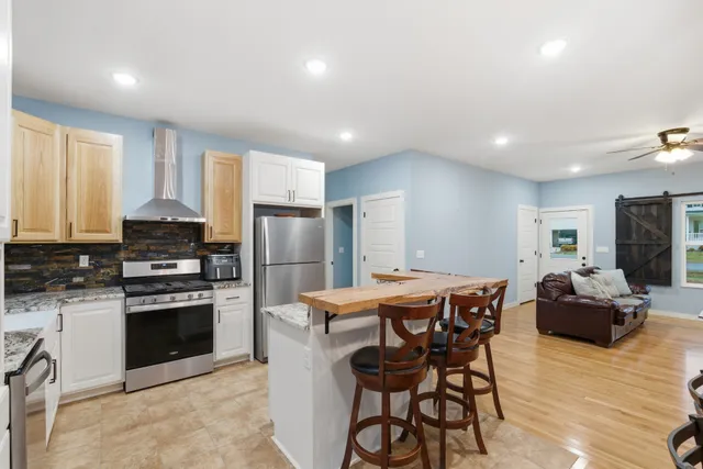 a kitchen with stainless steel appliances granite countertop a stove a sink a microwave a dining table and chairs