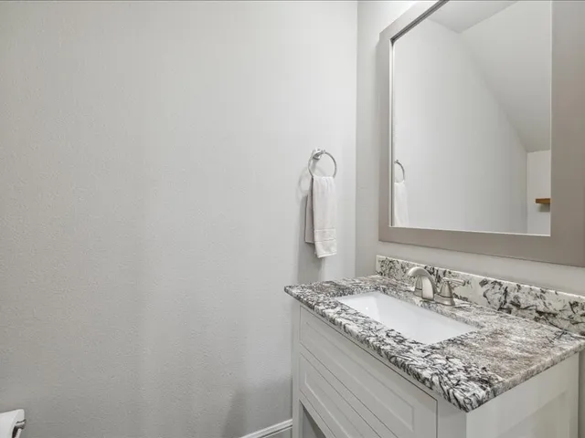 a bathroom with a granite countertop sink and a mirror