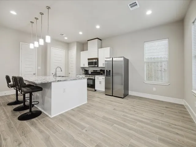 a kitchen with stainless steel appliances kitchen island a table chairs refrigerator and microwave