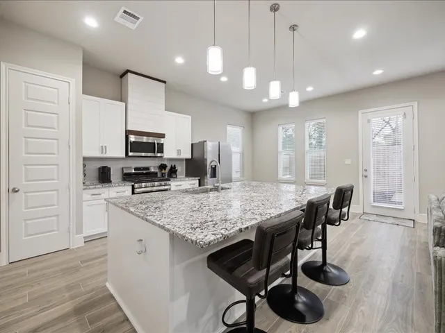 a kitchen with stainless steel appliances kitchen island granite countertop a stove a sink a dining table and chairs with wooden floor