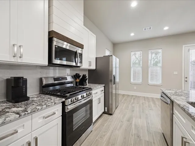 a kitchen with stainless steel appliances granite countertop a stove a sink and a refrigerator