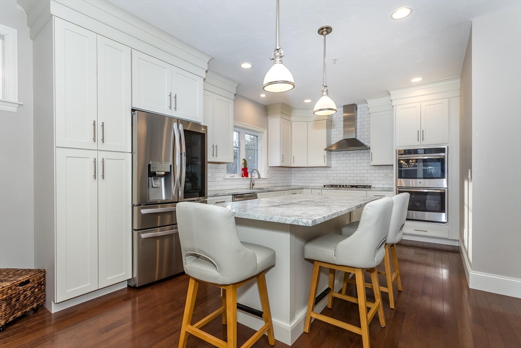 25 Brookview Road, Unit 25 Franklin, MA 02038 - Photo 8 of 28 a kitchen with stainless steel appliances granite countertop a stove a refrigerator a kitchen island a dining table and chairs with wooden floor