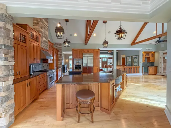 a large kitchen with stainless steel appliances kitchen island granite countertop a table and chairs in it