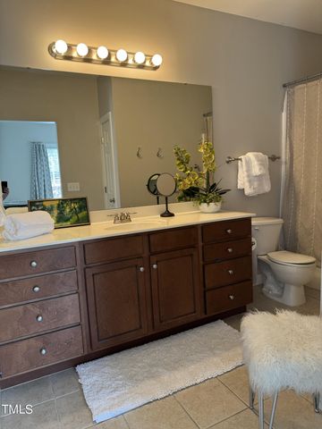 a spacious bathroom with double vanity sink a toilet and a mirror