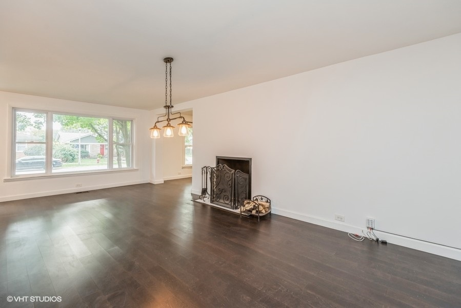 8640 East Prairie Road Skokie, IL 60076 - Photo 4 of 39 a view of a room with wooden floor exposed radiator and windows