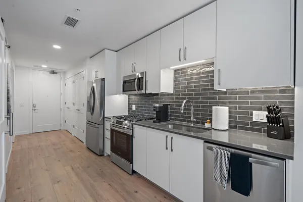 a kitchen with stainless steel appliances a sink dishwasher a refrigerator a stove and oven with wooden floor